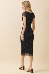 woman wearing a black fitted midi dress with floral patterns and cap sleeves, showing the back view