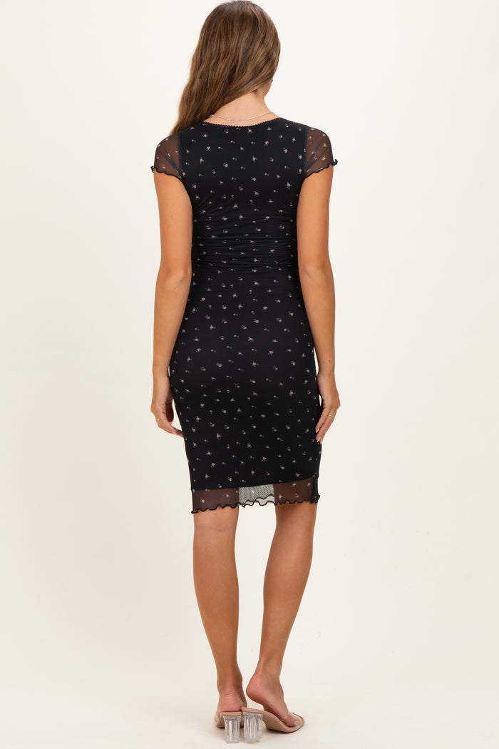 woman wearing a black maternity dress with short sleeves and floral print, showing a fitted silhouette from the back