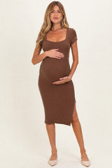 woman wearing a brown ribbed maternity dress with a scoop neckline and side slit, holding her baby bump