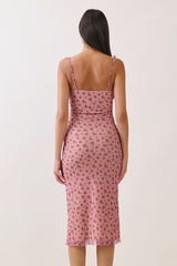 woman wearing a pink midi dress with a floral print and thin straps, viewed from the back