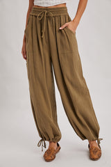 woman wearing olive green gauzy wide-leg pants with an elastic waistband and side pockets