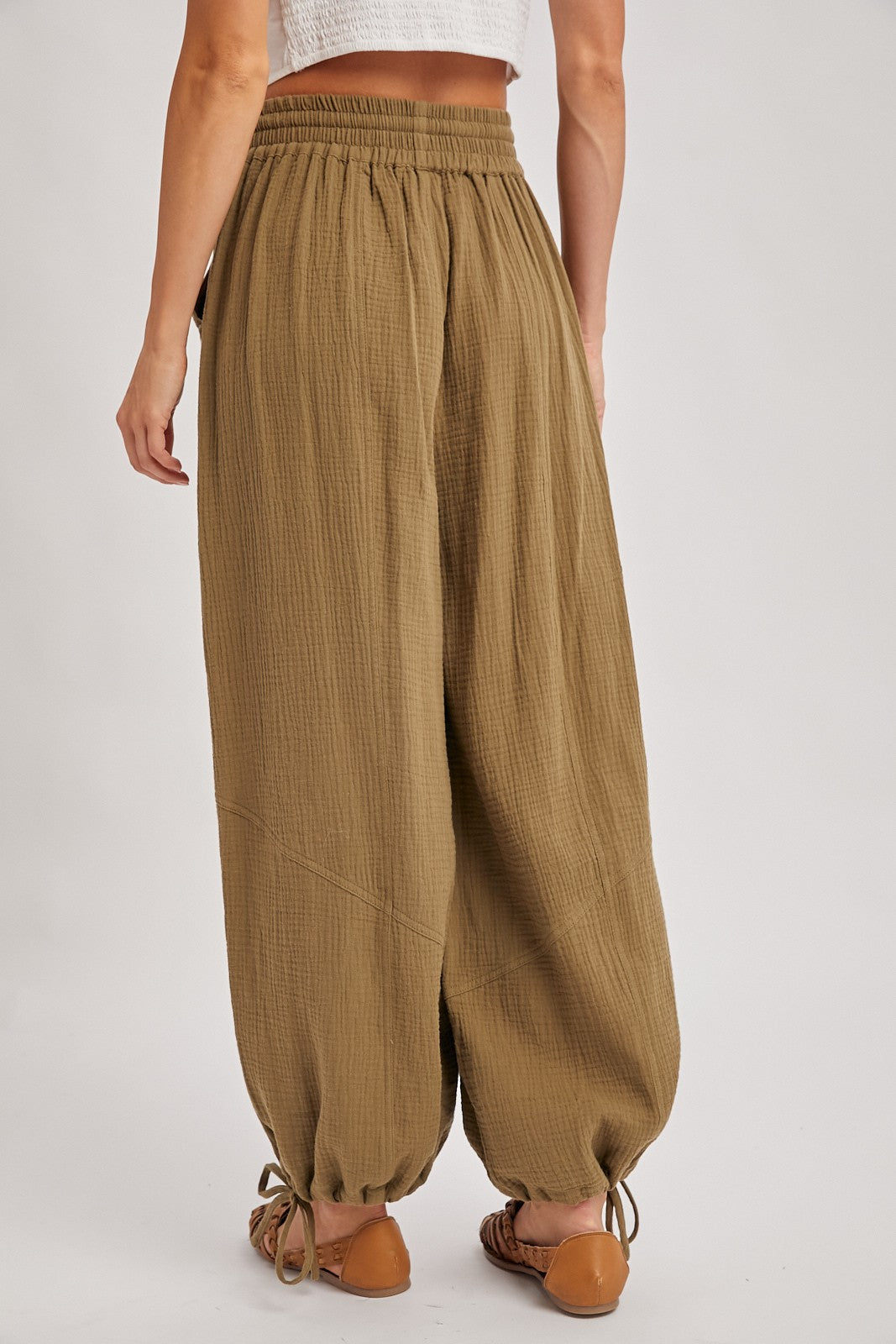 woman wearing olive green gaucho pants with an elastic waistband and drawstring detail at the ankle, viewed from the back