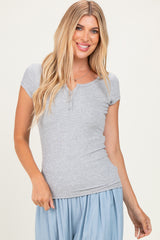 woman wearing a light gray short sleeve henley top with a scoop neckline and buttons, smiling at the camera