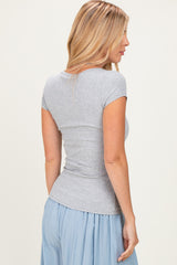 woman wearing a light grey short sleeve fitted top with a scoop neck and a blue flowy skirt