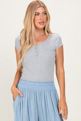 woman wearing a gray short sleeve henley top with button details and a relaxed light blue skirt