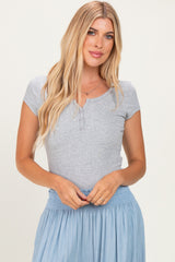 woman wearing a grey short sleeve henley top with buttons, styled with a light blue skirt