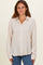 woman wearing a light beige striped button-up shirt with long sleeves and a relaxed fit paired with blue jeans