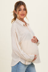 woman wearing a light beige maternity shirt with thin stripes and holding her baby bump