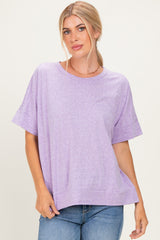 woman wearing a light purple oversized t-shirt with short sleeves and a relaxed fit, standing against a neutral background