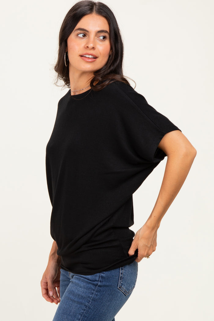 woman wearing a black loose-fit short sleeve top with side slits and blue jeans
