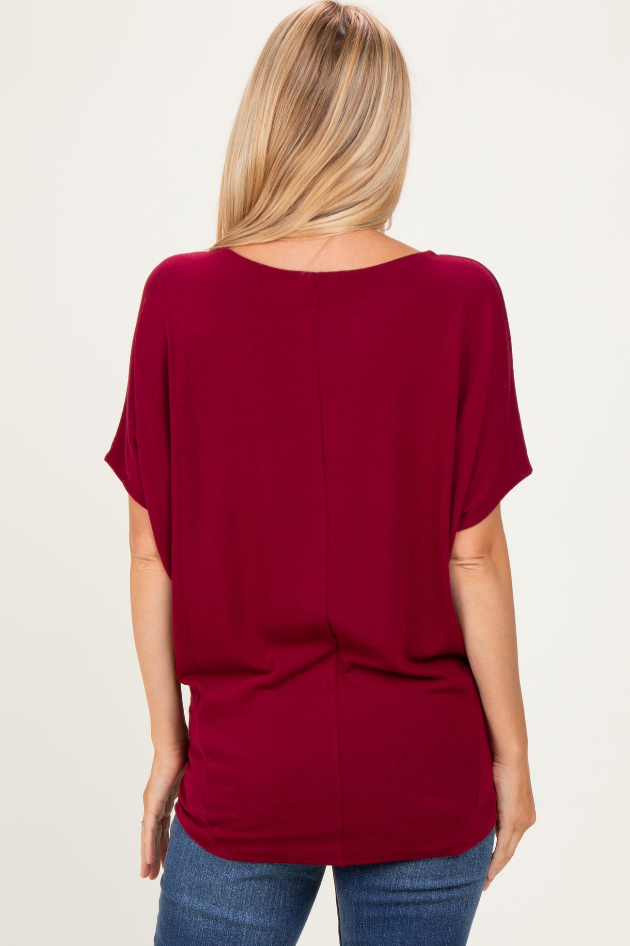 woman wearing a burgundy short sleeve top with a relaxed fit and scoop neckline, viewed from the back