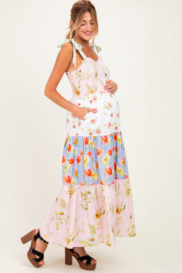 woman wearing a floral maternity maxi dress with tiered design and bow straps, showing her baby bump
