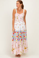 woman wearing a floral maxi dress with a smocked bodice and tiered color blocks in pink, blue, and white