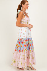 woman wearing a floral maxi dress with a fitted bodice and tiered skirt in various pastel colors and floral patterns