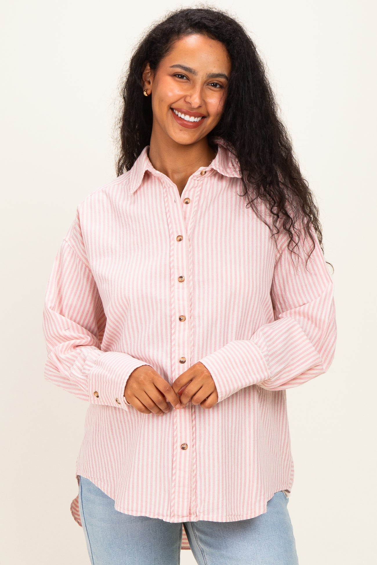 woman wearing a pink and white striped maternity button-up shirt with long sleeves and a relaxed fit