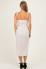 woman wearing a light pink lace midi dress with adjustable spaghetti straps and a fitted silhouette