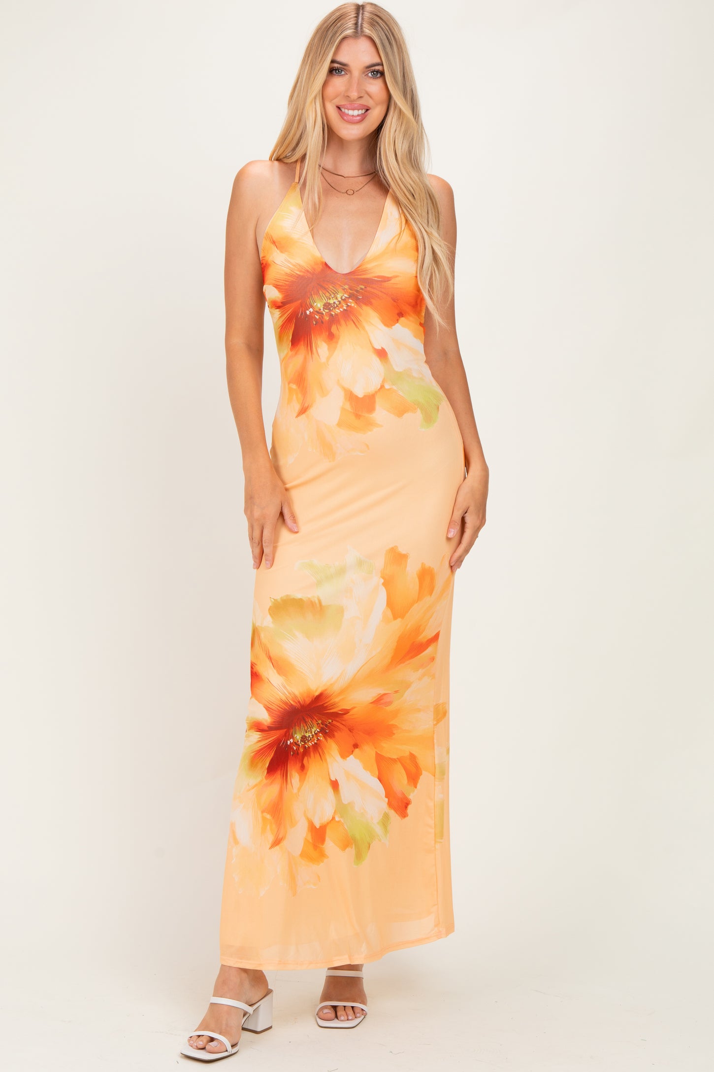 woman wearing an orange floral maxi dress with a deep V-neckline and spaghetti straps