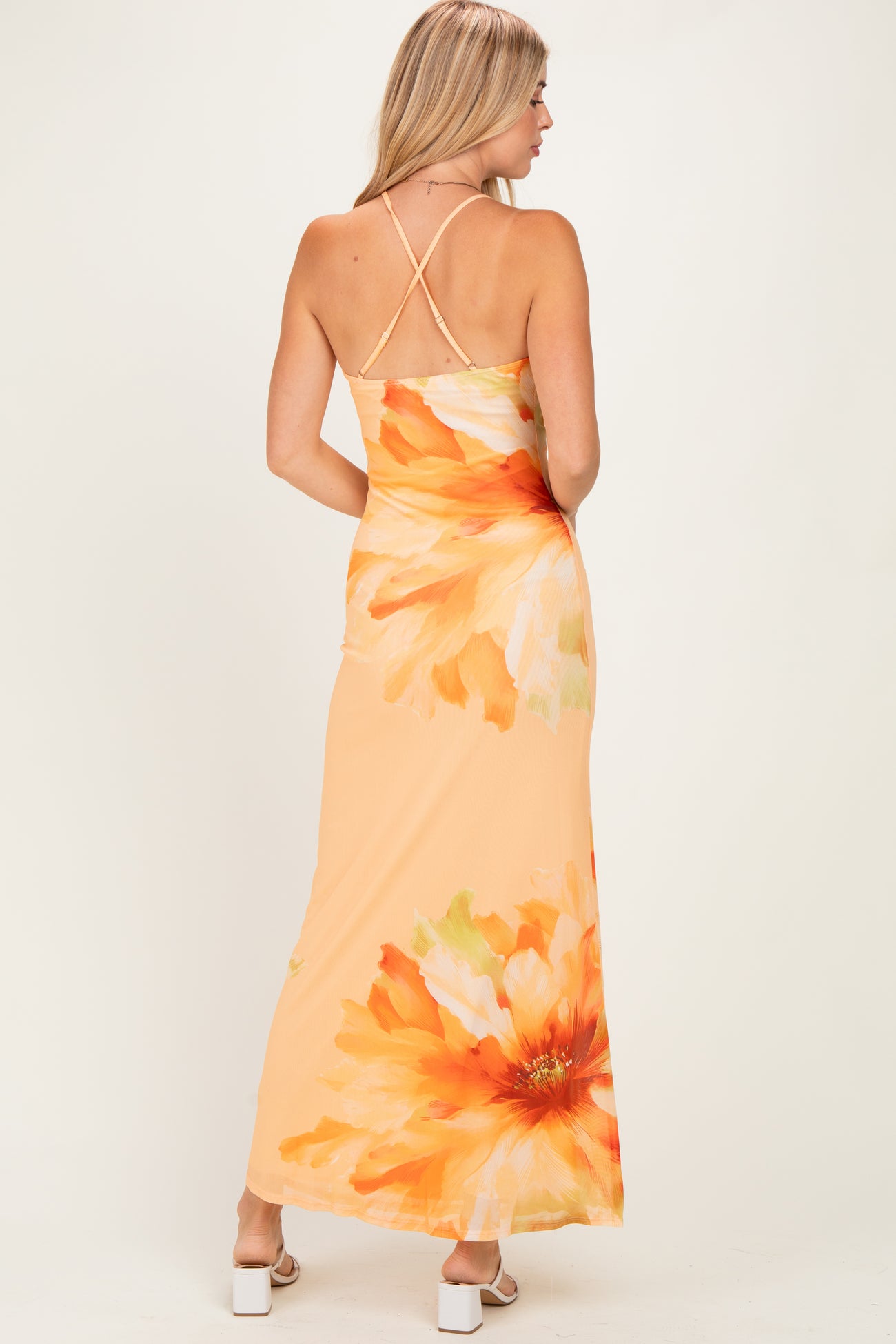 woman wearing an orange floral maxi dress with a back cross strap detail