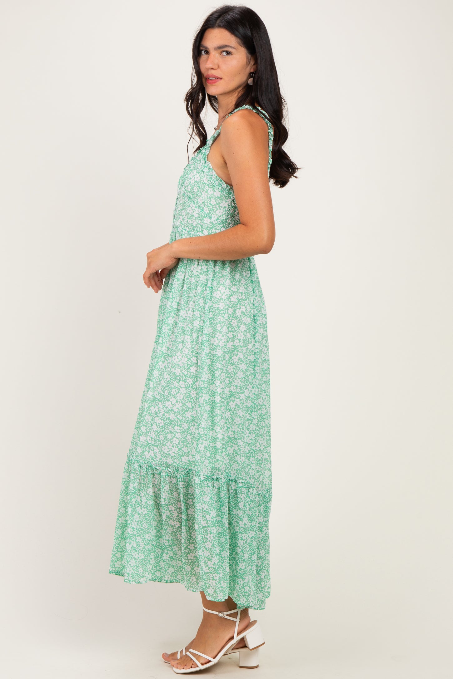 woman wearing a green floral maxi dress with adjustable straps and a tiered skirt