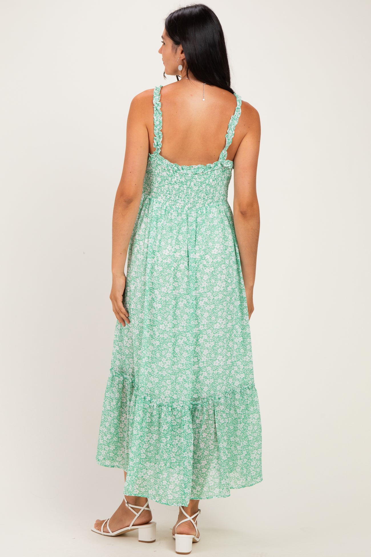 woman wearing a back view of a green floral maxi dress with ruffled straps and a tiered hem