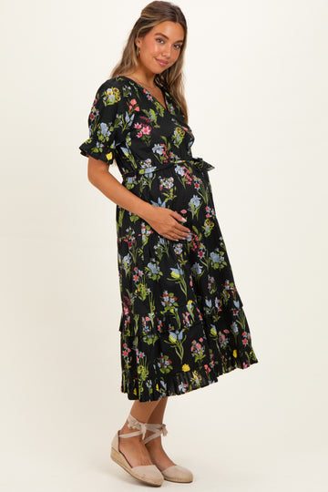 woman wearing a black floral maternity dress with ruffled hem and a visible baby bump