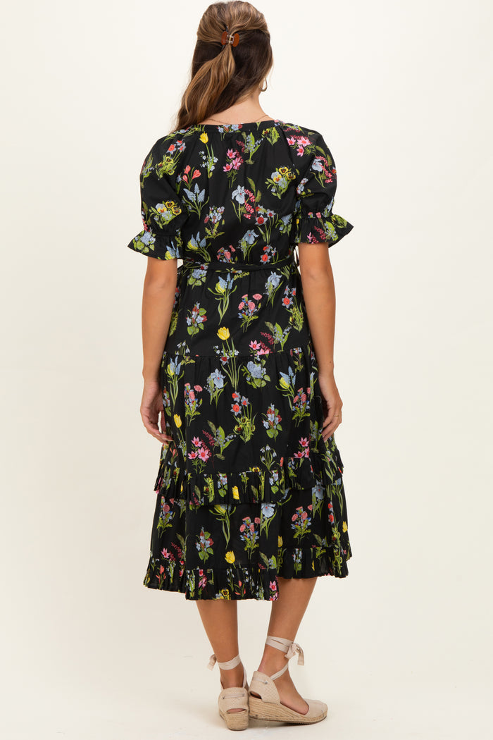 woman wearing a black floral print maternity dress with puff sleeves and ruffle detailing on the skirt