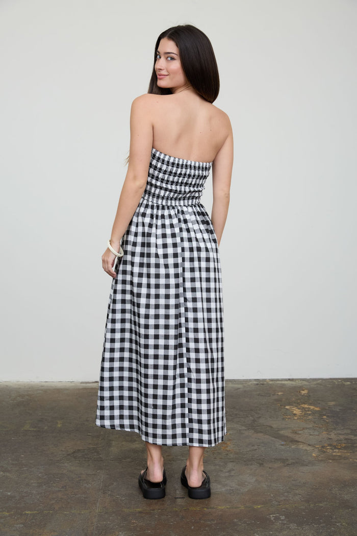woman wearing a black and white checkered strapless maxi dress, showing the back view
