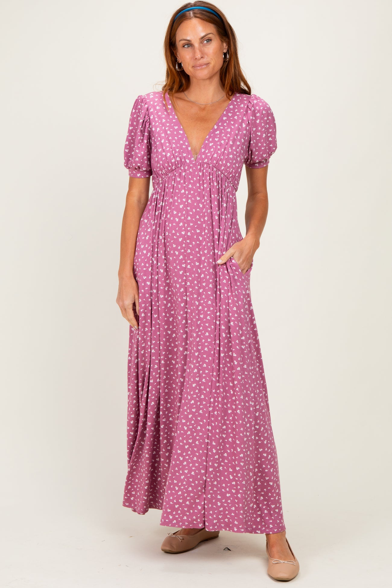woman wearing a pink maxi dress with puff sleeves and a v-neck, featuring a white polka dot pattern and side pockets