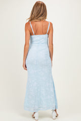 woman wearing a light blue floral maternity maxi dress, showing a fitted bodice and flowing skirt from the back