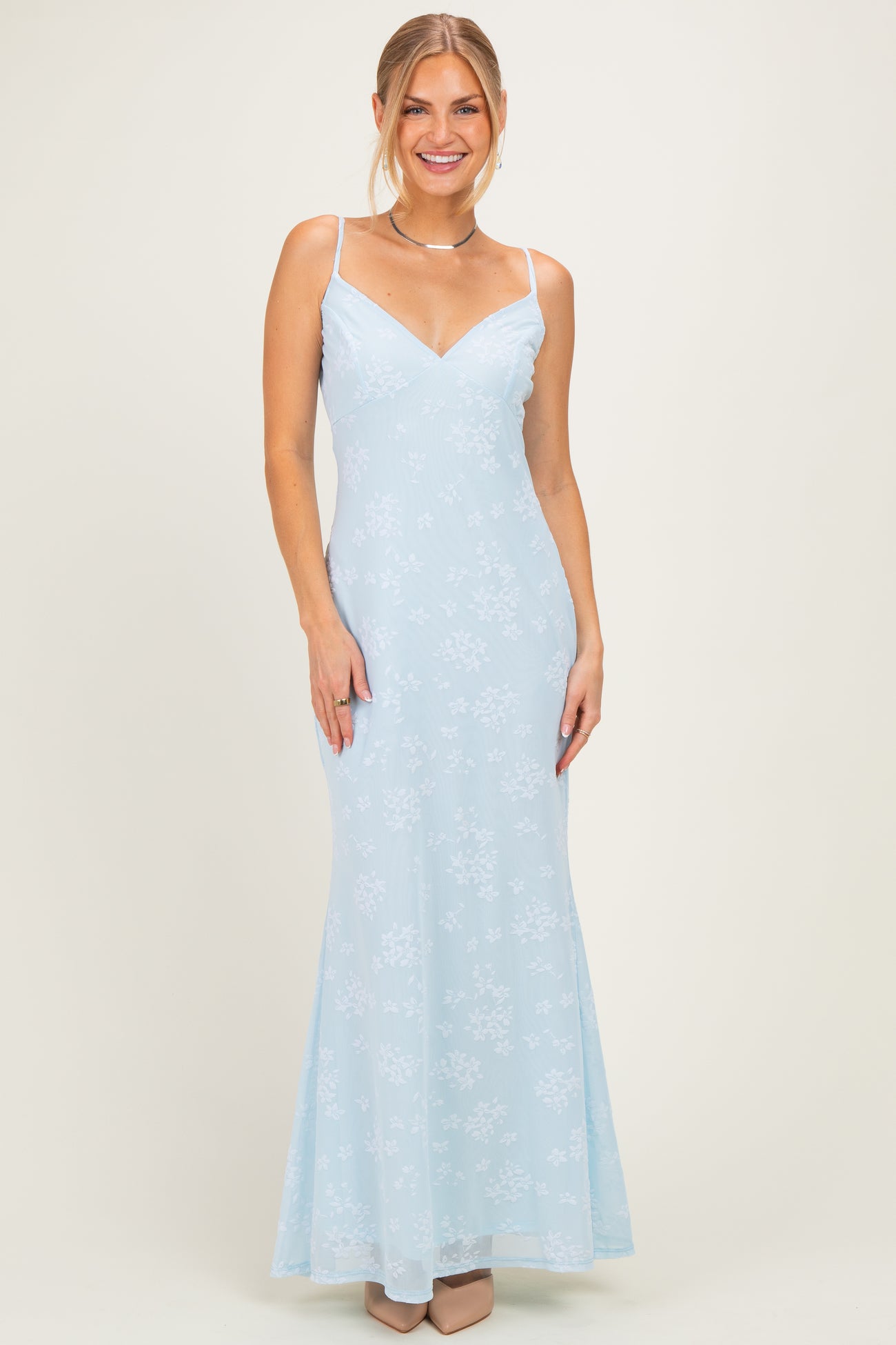 woman wearing a light blue floral evening gown with thin straps and a flared skirt