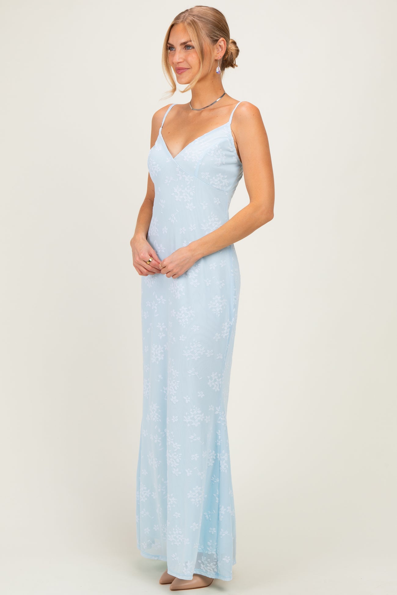woman wearing a light blue floral maxi dress with thin straps and a fitted silhouette
