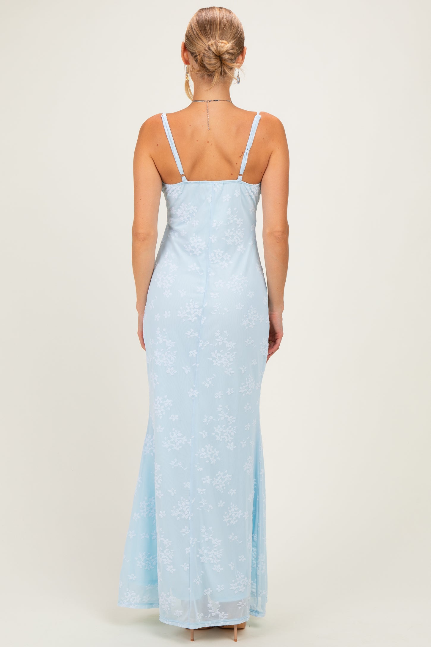 woman wearing a light blue floral maxi dress with thin straps, showing the back view