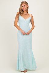 woman wearing a light mint green floral print maxi dress with thin straps and a fitted bodice