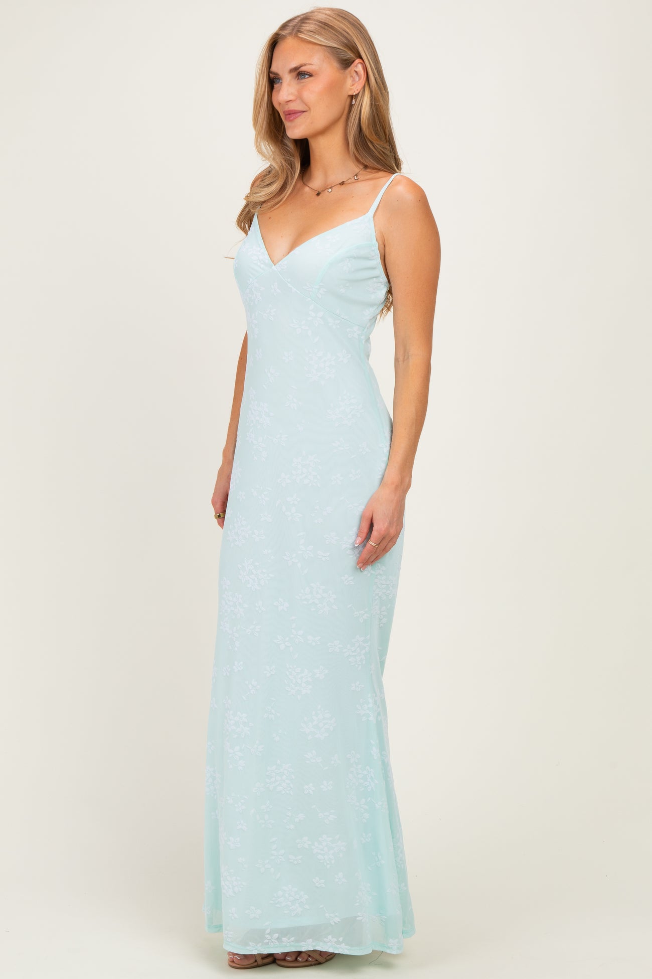 woman wearing a light mint green floral maxi dress with thin straps and a fitted silhouette