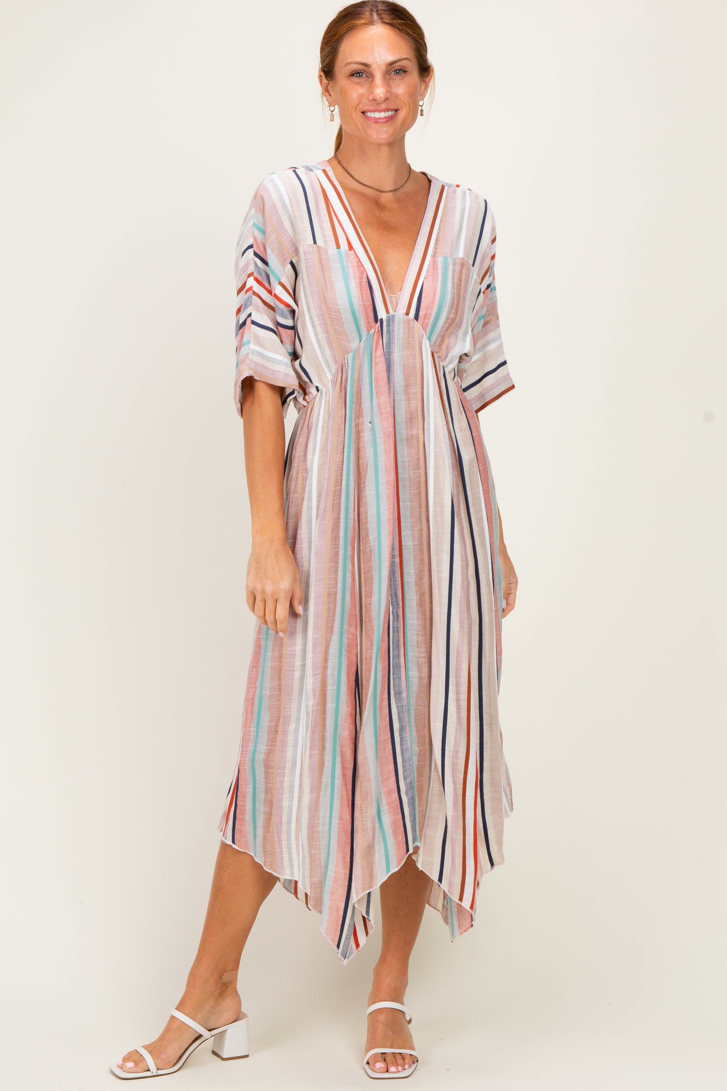 woman wearing a multi-striped maxi dress with a deep v-neck and short sleeves, standing and smiling