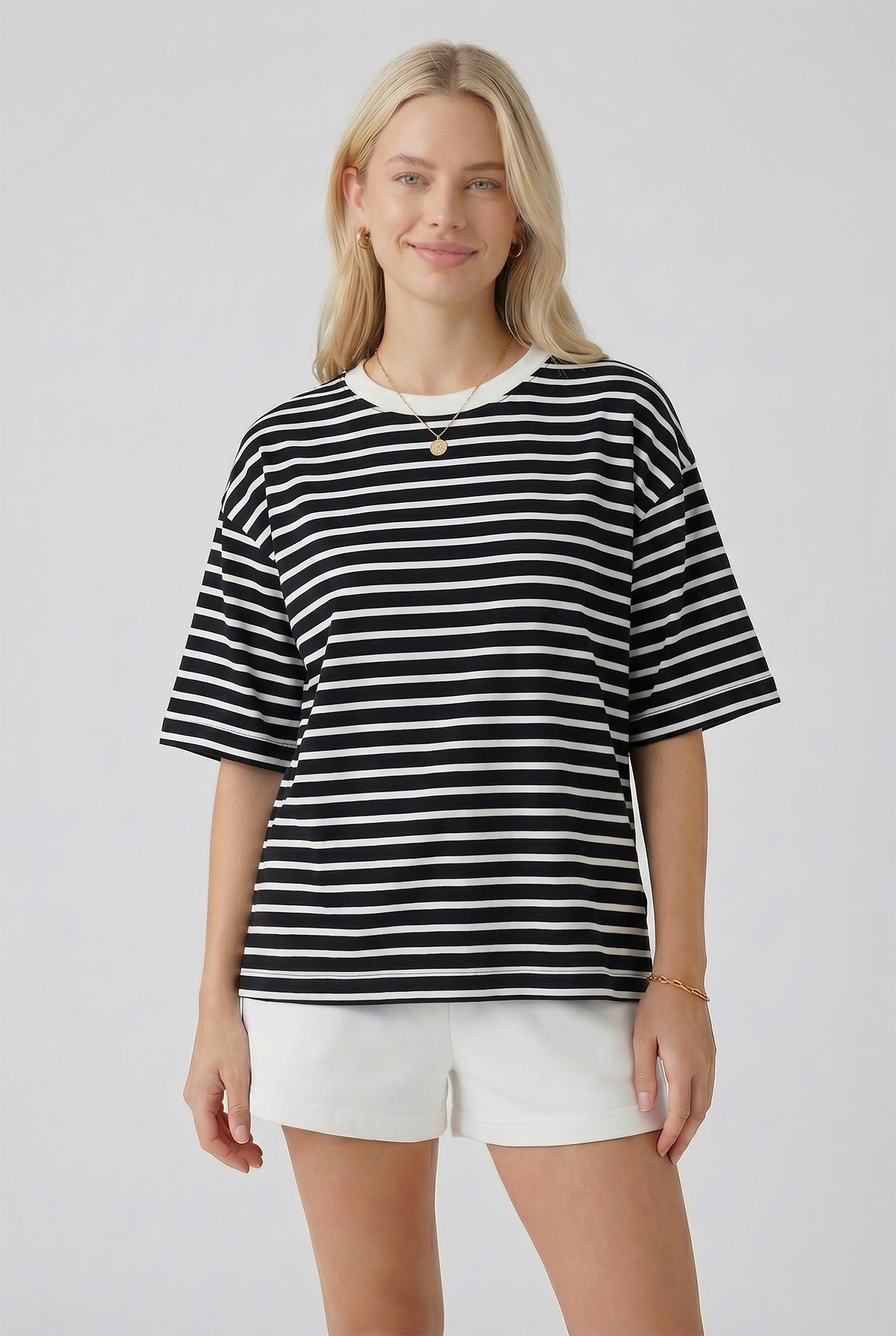 woman wearing a black and white striped oversized t-shirt paired with white shorts