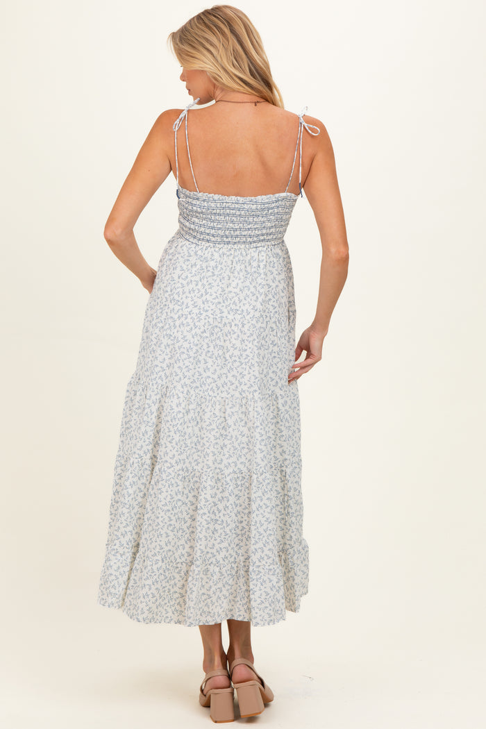 woman wearing a light blue floral maternity maxi dress with adjustable straps and a smocked back