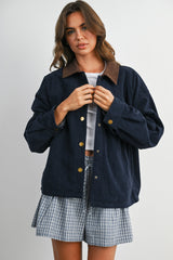 woman wearing a navy corduroy jacket with a brown collar, paired with a plaid mini skirt and a white top