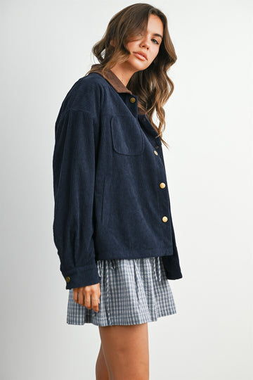 woman wearing a navy corduroy jacket over a gray and white checkered dress