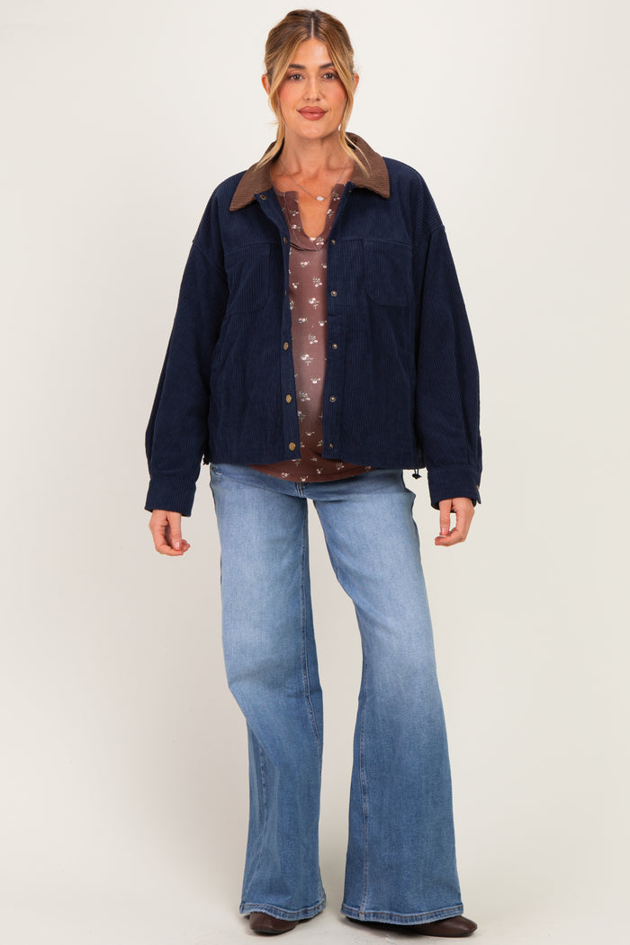 woman wearing a navy corduroy jacket over a brown floral maternity top and flared jeans, with a relaxed fit