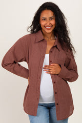 woman wearing a brown checkered maternity button-up shirt and holding her baby bump