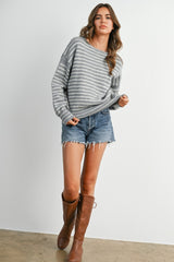 woman wearing a gray and white striped oversized sweater with denim shorts and brown knee-high boots