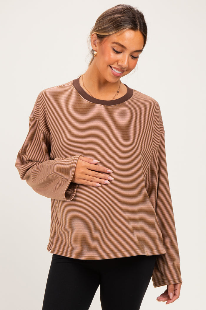 woman wearing a brown striped maternity top and holding her baby bump