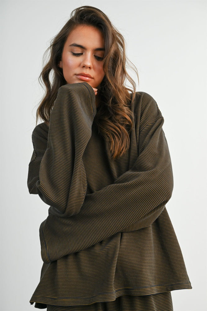 woman wearing an oversized brown striped long sleeve top with a relaxed fit and rolled cuffs
