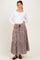 woman wearing a white long sleeve maternity top and a brown gingham tiered maternity skirt, holding her baby bump