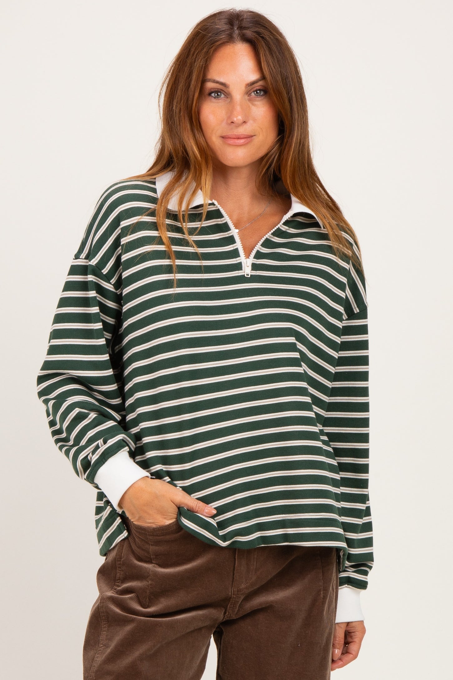 woman wearing a dark green and white striped long sleeve quarter zip top with a relaxed fit and white collar