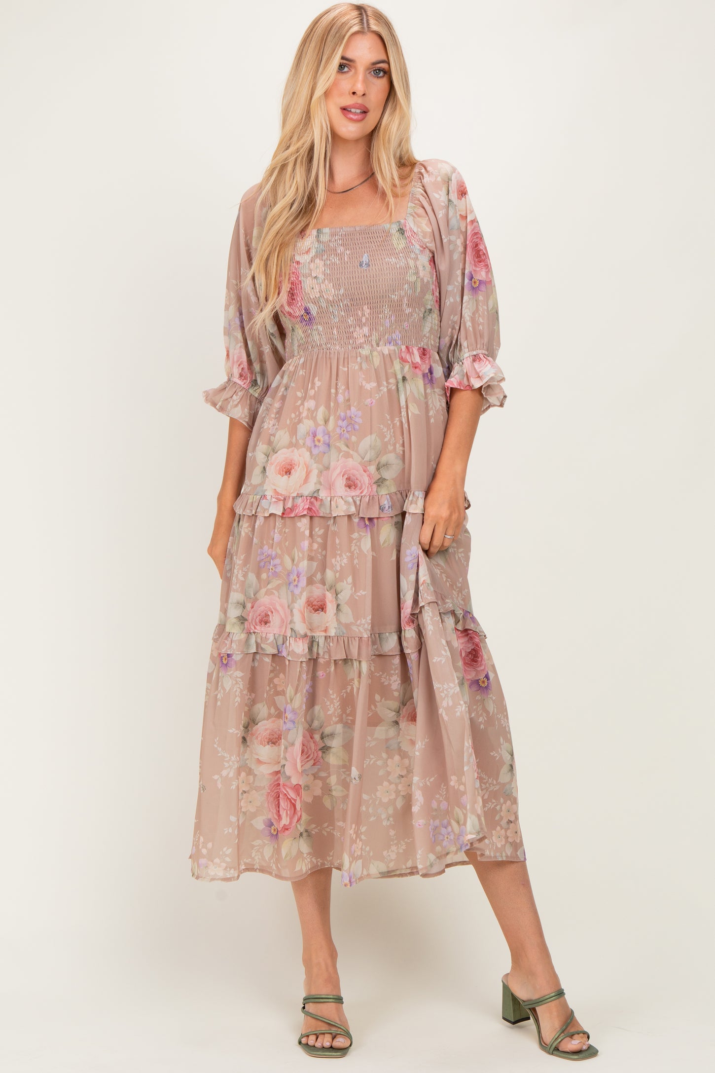 woman wearing a floral print maxi dress in muted pink with puff sleeves and tiered layers