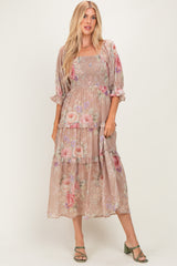 woman wearing a floral print maxi dress in muted pink with puff sleeves and tiered layers