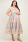 woman wearing a floral print maternity plus dress with adjustable straps and pockets, gently holding her baby bump