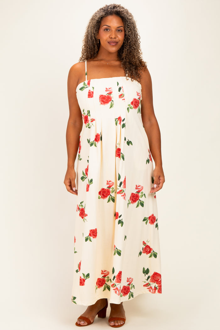 woman wearing a floral print maxi dress with red roses on a cream background, featuring adjustable straps and a flowing silhouette